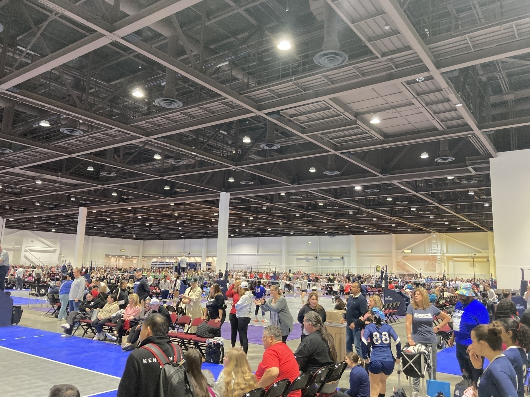 A large arena filled with volleyball players and their fans. 